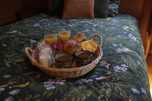 un panier de nourriture avec des oranges et des bougies sur un lit dans l'établissement Les Chanterelles La souris des champs, à Étival-Clairefontaine