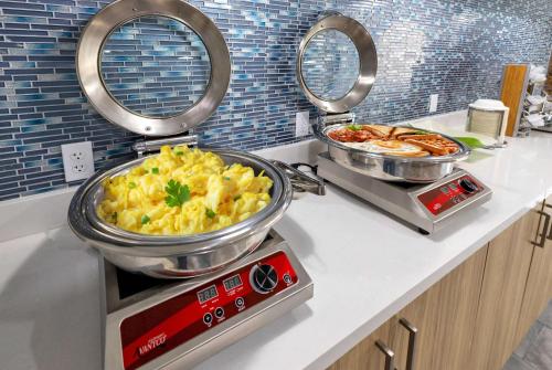 a kitchen with two pans of food on a counter at La Quinta Inn & Suites by Wyndham Jacksonville Mandarin in Jacksonville