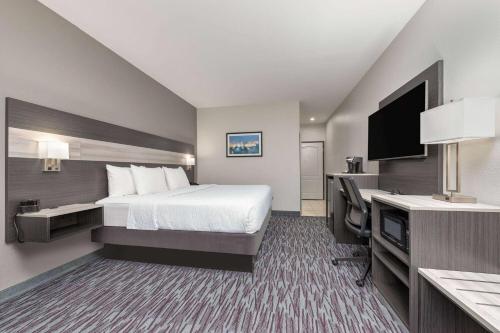a hotel room with a bed and a flat screen tv at La Quinta by Wyndham Allen at The Village in Allen