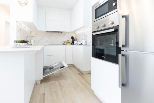 a kitchen with white cabinets and a stainless steel oven at Santanalodge - Piso a pocos metros de la playa in Pontevedra