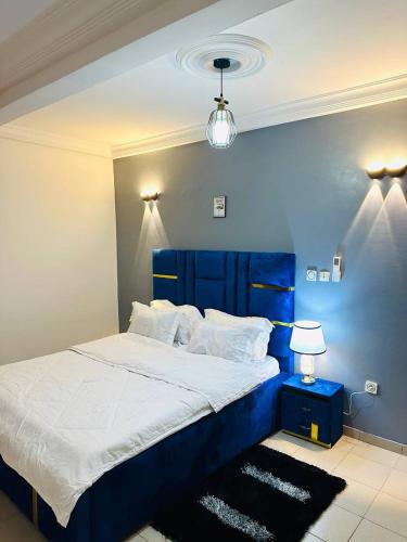 a bed with a blue headboard in a bedroom at KJM Home in Douala