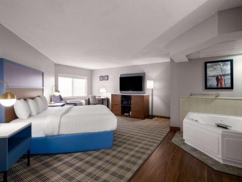 a hotel room with a bed and a bath tub at AmericInn by Wyndham Shakopee Near Canterbury Park in Shakopee