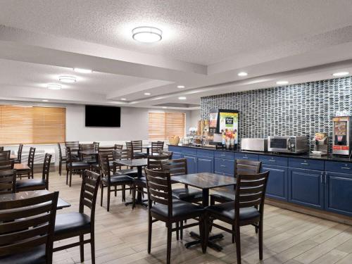 a restaurant with tables and chairs and a kitchen at AmericInn by Wyndham Shakopee Near Canterbury Park in Shakopee