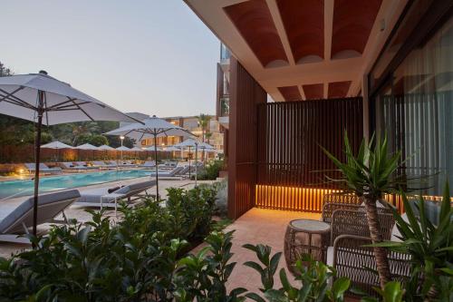 a resort with a pool with chairs and umbrellas at Cala San Miguel Ibiza Resort, Adults only, Curio Collection by Hilton in Puerto de San Miguel