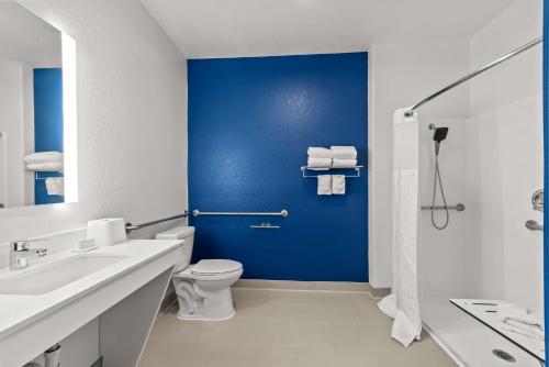 a bathroom with a toilet and a blue wall at Spark by Hilton Selma in Selma