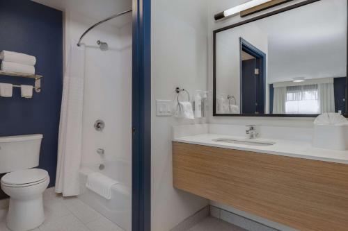 a bathroom with a sink and a toilet and a mirror at Spark By Hilton Santa Nella in Santa Nella