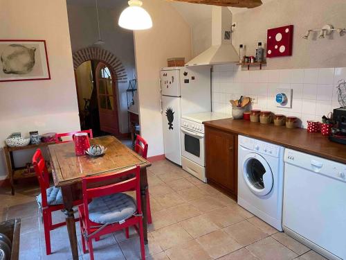 a kitchen with a table and a washing machine at Petite maison des Boirôts 3 chambres in Lenax