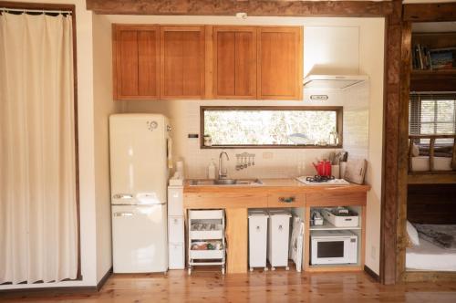 a kitchen with a white refrigerator and a sink at Yamakujira 焚火とBBQを楽しめる海辺プライベートコテージ 山鯨荘 in Minamiboso