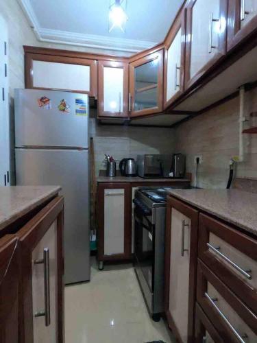 a kitchen with a stainless steel refrigerator and wooden cabinets at Cozy Modern Comfort-2 Bed Escape at Madinaty in Madinaty