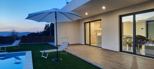 a patio with two chairs and an umbrella at Sunny Haven-Villa in Ponte de Lima