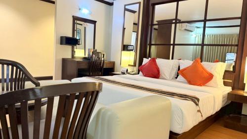 a bedroom with a large bed with orange and white pillows at Grand Business Inn in Bangkok