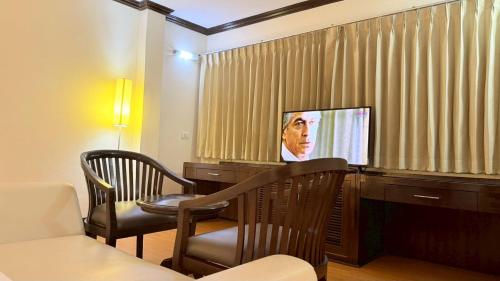 a living room with a television and a table and chairs at Grand Business Inn in Bangkok
