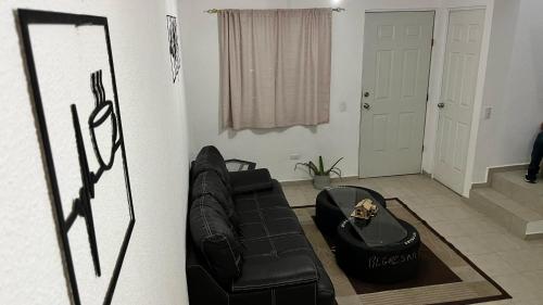 a black leather couch sitting in a living room at Casa Curicó Viñedos in Las Adjuntas