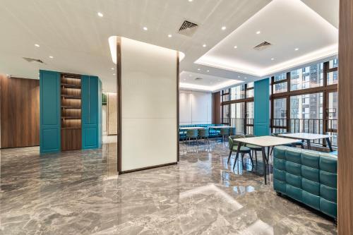 a lobby of a building with tables and chairs at Merrihod Hotel - Guangzhou South Station Jinlong Subway Station Branch in Shunde