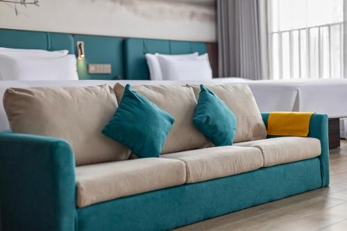 a couch with pillows on it in a room at Merrihod Hotel - Guangzhou South Station Jinlong Subway Station Branch in Shunde