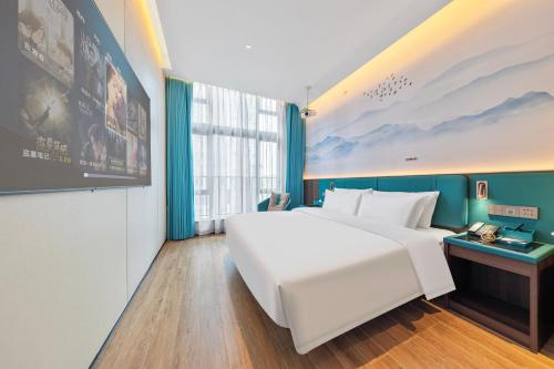 a large white bed in a room with a large window at Merrihod Hotel - Guangzhou South Station Jinlong Subway Station Branch in Shunde