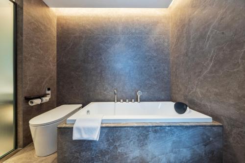 a bathroom with a bath tub and a toilet at Merrihod Hotel - Guangzhou South Station Jinlong Subway Station Branch in Shunde