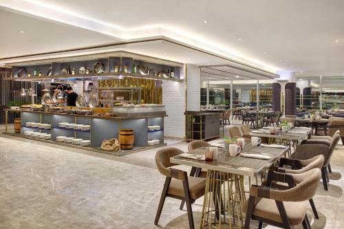 a restaurant with tables and chairs and a kitchen at Novotel Jakarta Cikini in Jakarta