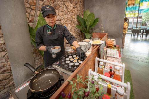 um homem a cozinhar comida num grelhador numa cozinha em Prana Resort Nandana em Bangrak Beach