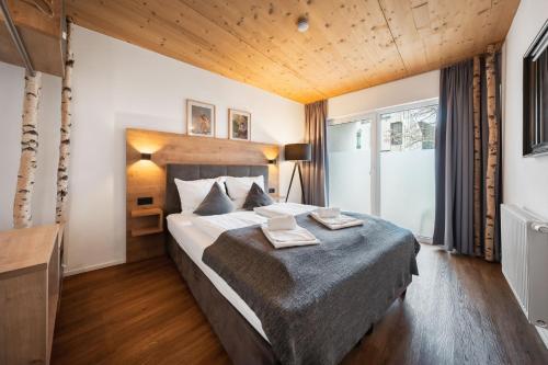 a bedroom with a large bed with a wooden ceiling at Das Sill by Inncomer in Innsbruck
