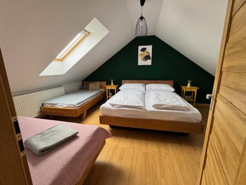 a attic bedroom with two beds and a green wall at Apartman pod Smokovcom in Dolný Smokovec