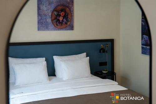 a bed with a blue headboard and white pillows at Hotel Botanica in Belgrade