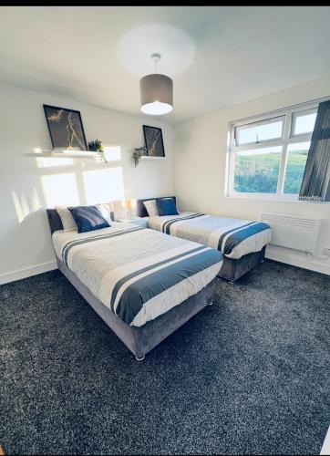 two beds in a room with two windows at SwankyApartmentDudleyNearM6 in Coseley