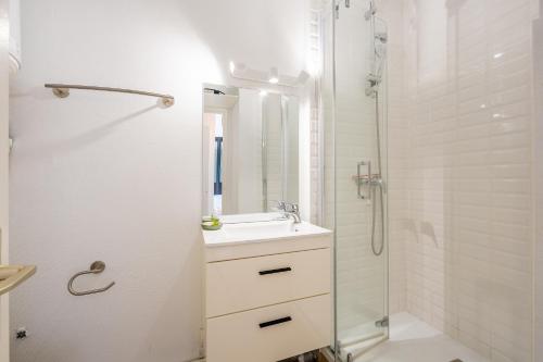 une salle de bain blanche avec un lavabo et une douche dans l'établissement Le Studio des Dunes - A 50m de la plage, à Soulac-sur-Mer