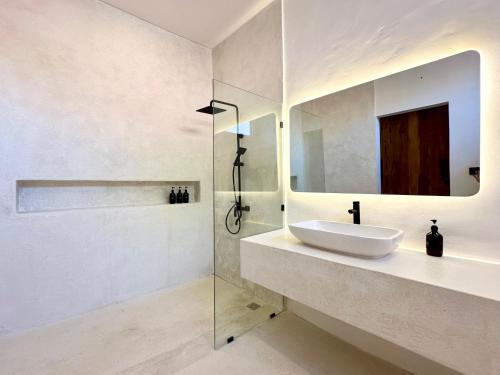 a white bathroom with a sink and a mirror at The Ulu Hills in Uluwatu