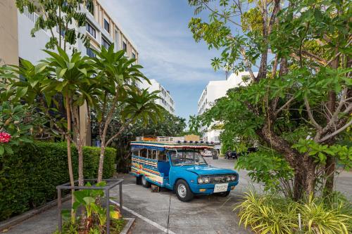a blue bus parked on a street next to trees at Recenta Phuket Suanluang in Phuket Town