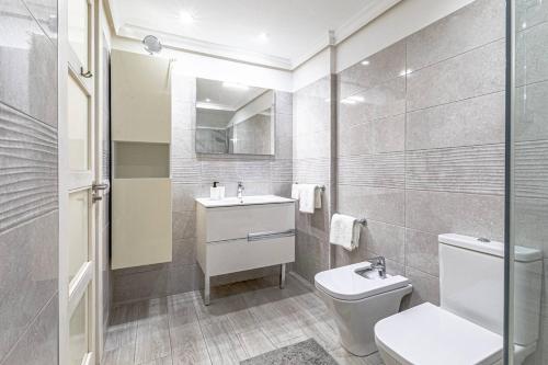 a white bathroom with a toilet and a sink at Santos Lerch Sol Apartment in Puerto de Santiago