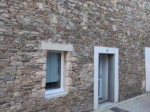 un mur en pierre avec deux fenêtres sur un bâtiment dans l'établissement La Chauvinière, à Montaigu-Vendée