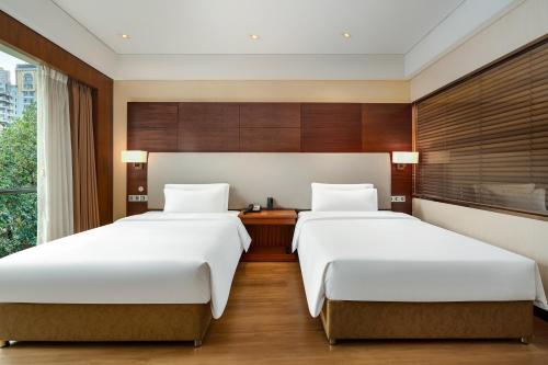 two beds in a hotel room with a window at Langlizi Hotel in Chongqing
