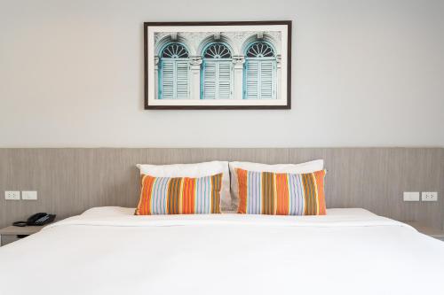a bed with two pillows and a picture above it at Recenta Phuket Suanluang in Phuket Town