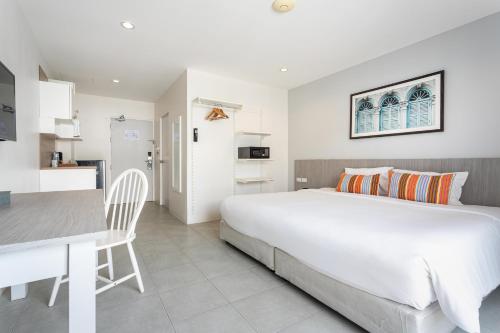a bedroom with a large white bed and a kitchen at Recenta Phuket Suanluang in Phuket Town