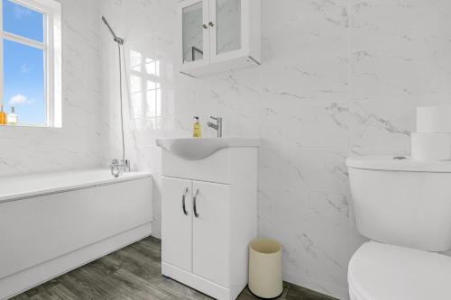 a white bathroom with a sink and a toilet at Spacious 5-Bedroom 2-Bath Home in Stanwell in Stanwell