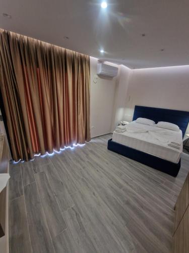 a bedroom with a bed and a large window at Joanna Suites in Sarandë