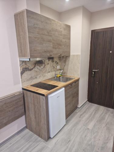a kitchen with a sink and a wooden cabinet at Joanna Suites in Sarandë
