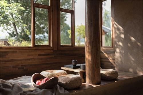 a room with two windows and a table with baskets at Shaxi Ancient Town Shiran Mountain Homestay in Jianchuan