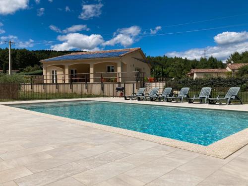 une piscine avec des chaises et une maison dans l'établissement Villa Luminières 2, à Sallelles