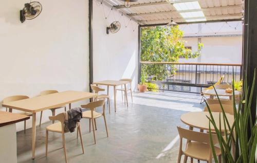 Una habitación con mesas y sillas y una gran ventana. en Muulao Hostel, en Vientiane