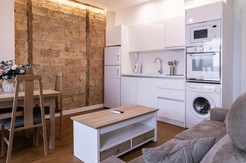 eine Küche und ein Wohnzimmer mit weißen Schränken und einem Tisch in der Unterkunft El Rincón de Pilar in Córdoba