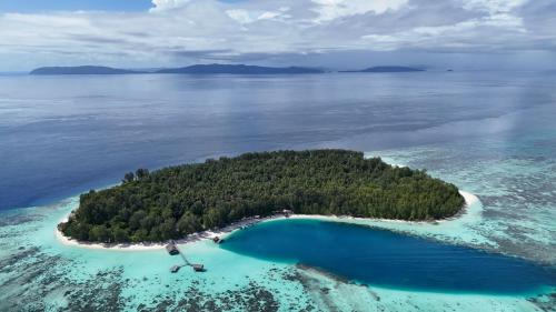 an island in the ocean with blue water and trees at Wai Resort - Raja Ampat in Pulau Birie