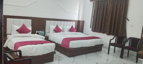 a bedroom with two beds with pink pillows at Buddha Dham in Mathura