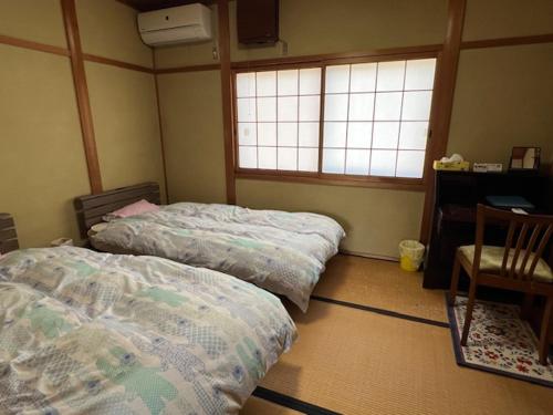 a bedroom with two beds and a desk and two windows at Houtouji Temple in Yoshino