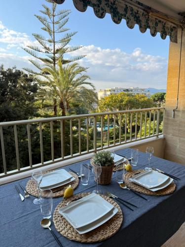 une table bleue avec des assiettes et des verres sur un balcon dans l'établissement Chic 2 bedroom with Huge Terrace and Pool Cannes, à Cannes