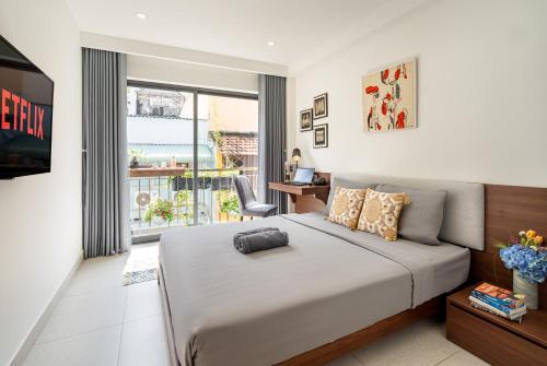 a bedroom with a bed and a desk and a window at Mersey Ben Thanh Saigon Apart'Hotel in Ho Chi Minh City