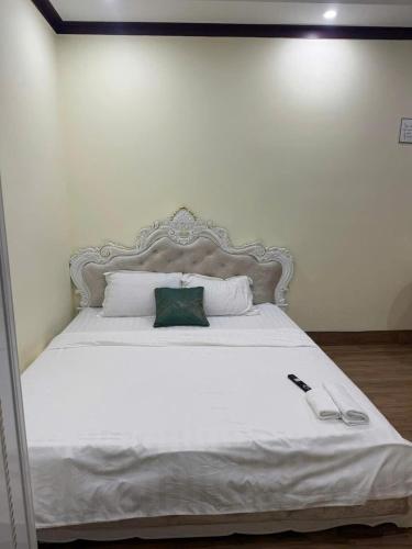 a large white bed with a green pillow on it at Thảo Nguyên Hotel in Kinh Dinh