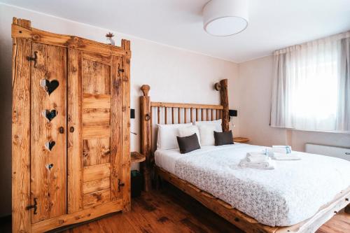 a bedroom with a bed and a large wooden cabinet at Serendipity Hotel in Sauze dʼOulx