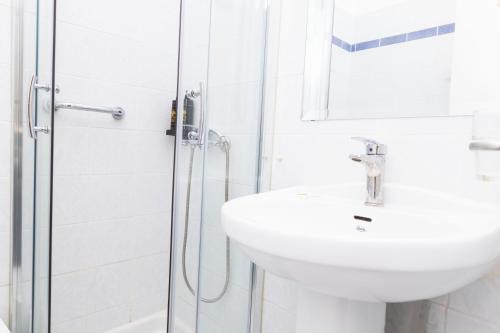 a white bathroom with a sink and a shower at Hermes Xenon in Corfu Town